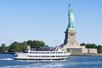 A white cruise boat with tourists standing on it's top deck sailing past the Statue of Liberty on a sunny day on the 60-Minute Statue of Liberty Sightseeing Cruise.