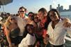 A group of friends huddled together posing for a photo with the sun shining on them on the 60-Minute Statue of Liberty Sightseeing Cruise.