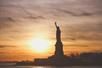 The Statue of Liberty with a bright orange sunset behind it on the 60-Minute Statue of Liberty Sightseeing Cruise.