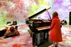 A girl looking at the piano that seems to control the art projection with several other couples comfortably enjoying the room of art at ARTECHOUSE Washington DC.