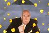 Adam London in a black suit holding an umbrella to shield himself from the yellow rubber ducks raining around him.