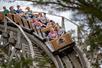 A roller coaster car full of people screaming while going around a corner on the wooden coaster The Outlaw at Adventureland.