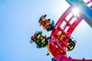 View looking up at park guests strapped into their seats on the red Dragon Slayer coaster with some guest upside down on a sunny day at Adventureland.