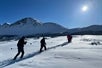 Group of hikers with trekking poles in hand trekking along a snow-covered trail in Chugach State Park.