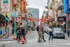 People exploring Chinatown with views of lanterns and Chinese symbols on the buildings on the Alcatraz Island Ticket with Guided Chinatown and North Beach Tour & Fortune Cookie Factory in San Francisco California, USA.
