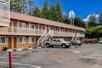 The parking lot and the exterior walkway for the Americas Best Value Inn on a sunny day in Fort Bragg, California.