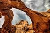A stunning view looking up at the famous "Double Arch" with a cloudy sky overhead at  Arches National Park in Utah