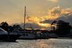 A dock full of boats with trees in the background and an orange sunset and clouds in the sky in North Myrtle Beach, South Carolina.