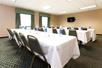 Meeting space with tables, chairs and a flat-screen TV.