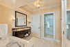 Private bathroom with glass-enclosed shower, bath tub, and sink with mirror.