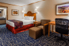 One King bed, seating area, and work desk and chair inside a guest room at SureStay By Best Western Kansas City Country Inn North.