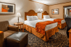 Two double beds and an oversized chair inside a guest room at SureStay By Best Western Kansas City Country Inn North.