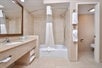 Fresh towels, bathtub, and bathroom amenities inside a private bathroom.