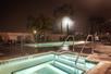 Outdoor pool and hot tub at night.
