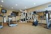 A fitness center with several pieces of cardio equipment and a weights machine in front of a large mirror.