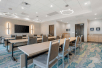 Spacious meeting room with chairs, long tables, and flat-screen TV.