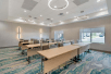 Well-lit meeting room with chairs and long tables.