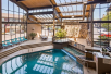 Indoor pool with water fountain, lounge chairs and floor to ceiling windows.