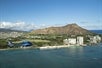 A helicopter as it flies by a city coastline with a mountain in the background on the Blue Skies of Oahu Helicopter Tour in Hawaii USA.