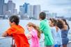 Six children leaning against the railing of the cruise boat on the Boston Historic Harbor Cruise with the city of Boston in the background.