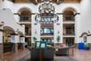 A lobby with sofa seating and high ceiling, sun roof, large chandelier, and archways showing the upper level walkways.