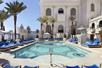 A small outdoor swimming pool with clear blue water and blue lounge chair lining the sides on a sunny day at Caesars Palace Hotel & Casino.
