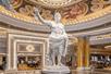 A white stone statue of Julius Caesar with his arm up in the ornate white and gold lobby of Caesars Palace Hotel & Casino.