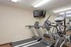Fitness room with two treadmills, and other cardio equipment, and a flat-screen TV.
