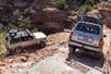 Two NAVTEC land cruisers navigating Elephant Hill in the Needles District of Canyonlands National Park on a sunny day.