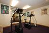 A fitness center with a treadmill, stair machine, and bike in front of a large mirror at Cloverdale Wine Country Inn & Suites.