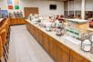A large breakfast buffet area with countertops lined with breakfast foods and drinks and a long table to the left.