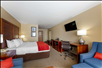 1 King bed, flat-screen TV, work desk, and a comfortable seating inside a guest room.