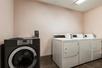 A hotel guest laundry room with a black washer next to a set of white washers and dryers at the Country Inn & Suites.