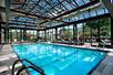 Indoor pool surrounded by glass windows and glass ceiling for natural lighting.