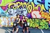 Two girls on their segway's in front of the Kakaako Mural on the Diamond Head Segway Tour, Honolulu Hawaii.