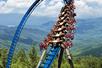 Wild Eagle roller coaster full of people going around a bend with the Smokies in the background at Dollywood in Pigeon Forge, Tennessee, USA.