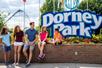 A family sitting on a brick wall in front of the sign for Dorney Park on a sunny day in Allentown, Pennsylvania.
