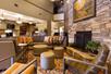 A lounge area in the lobby of the Drury Inn & Suites Flagstaff with a large "L" shaped couch, several ottomans and chairs, and a fireplace.