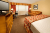 1 King bed, a work desk, a flat-screen TV and a sofa inside a non-smoking room at Drury Inn & Suites Phoenix Airport, AZ.