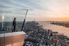 A woman enjoying the view off of the sky deck at sunset with the city in the distance at Edge New York.
