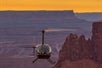 The Helicopter flying through the Canyonlands with the sunset behind it on the Edge of Canyonlands Moab Helicopter Tour in Moab Utah, USA.