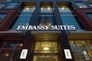 The bright white sign for the Embassy Suites above the glass front entrance in Denver, Colarado.