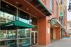 The exterior of a Starbucks with a small table with a green umbrella over it next to the Embassy Suites by Hilton Denver Downtown Convention Center.