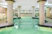 An abstract shaped indoor swimming pool with light green-blue water and pillars on both sides at the Embassy Suites by Hilton Portland Downtown.