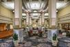 A large ornate lobby with several colums, seating areas, plants, and a large wooden front desk on the left side at the Embassy Suites by Hilton Portland Downtown.