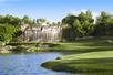 The Wynn Golf Club with bright green grass, a waterfall feature, and lots of trees on a sunny day in Las Vegas.