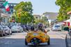View of a GoCar from behind with tourists wearing black helmets driving it down a busy street on the Experience San Diego GoCar Tour.
