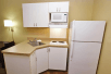 In-room kitchen refrigerator, stovetop, and microwave in a guest room.