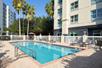 A small outdoor swimming pool with light blue water and lounge chairs on the sides on a bright and sunny day in Orlando.