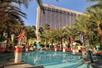 An outdoor swimming pool surrounded by palm trees and flamingo statues on a sunny day at the Flamingo in Las Vegas, Nevada.